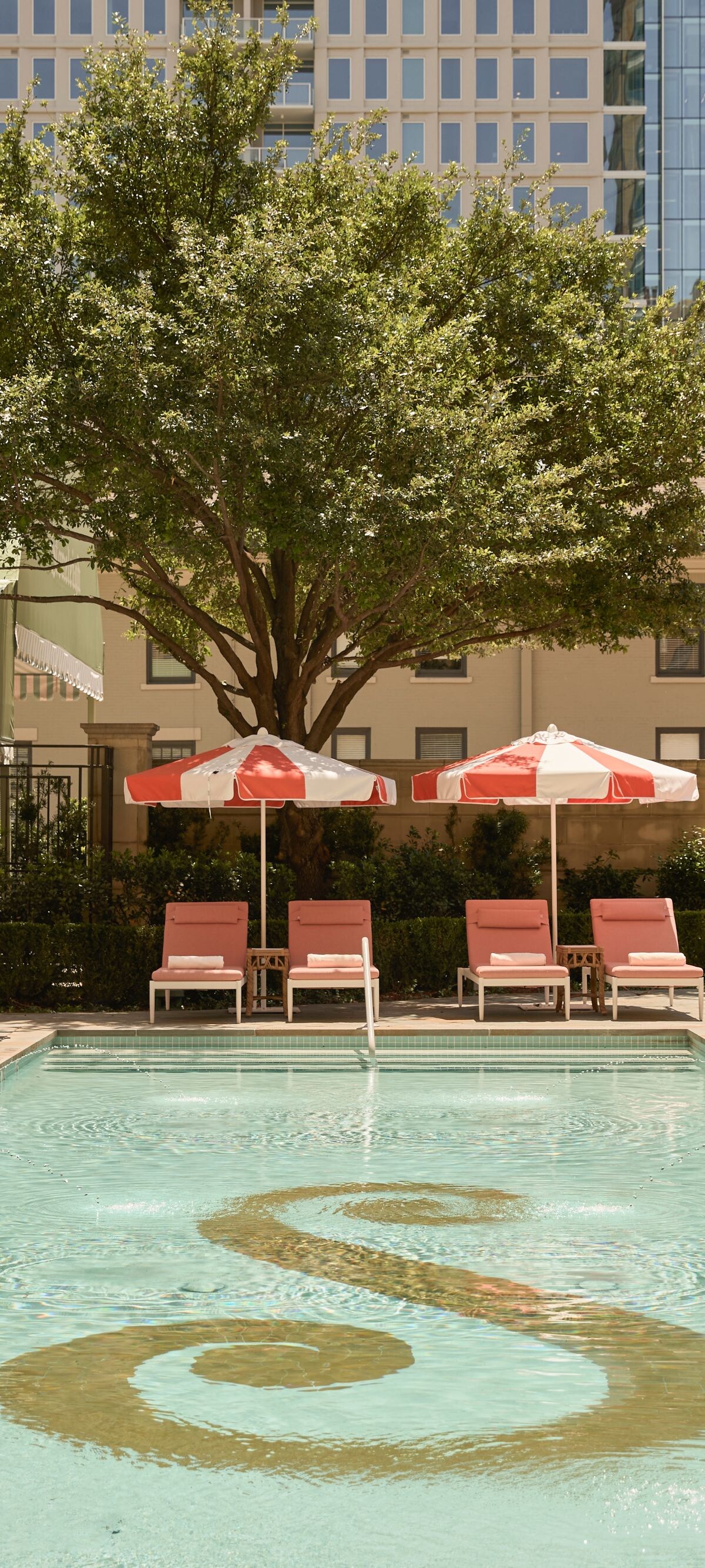 Outdoor pool with loungers and red umbrellas