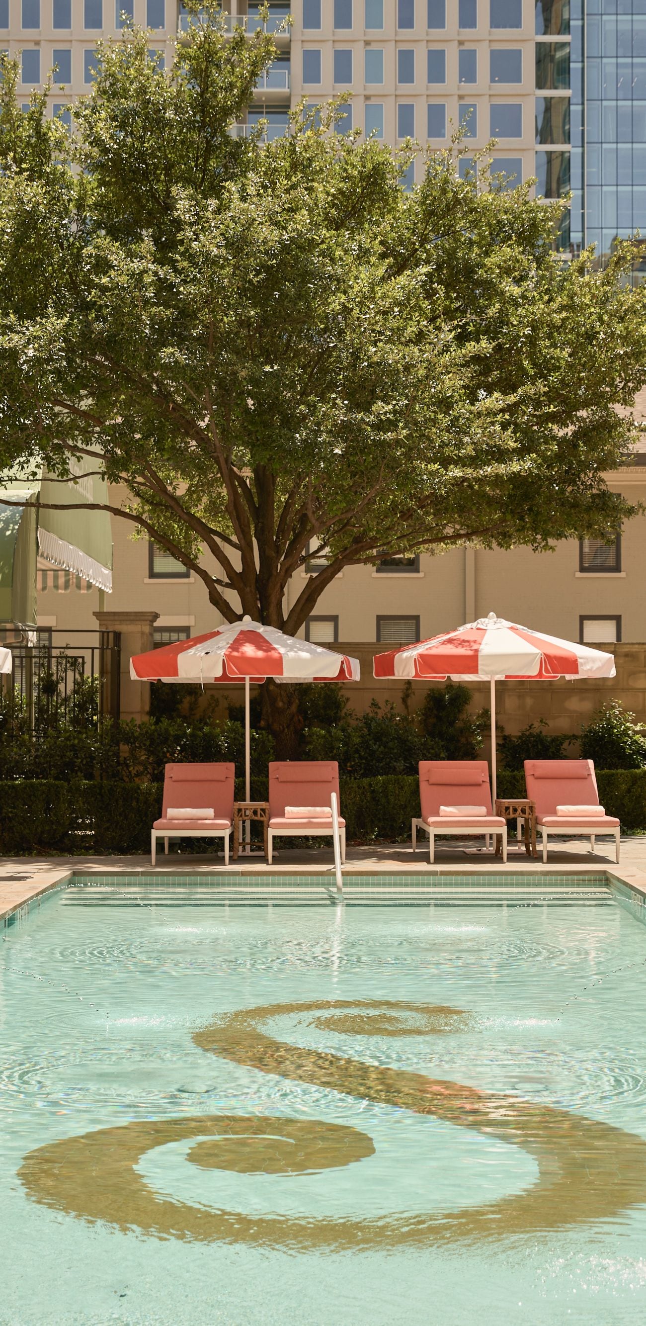 Outdoor pool with loungers and red umbrellas