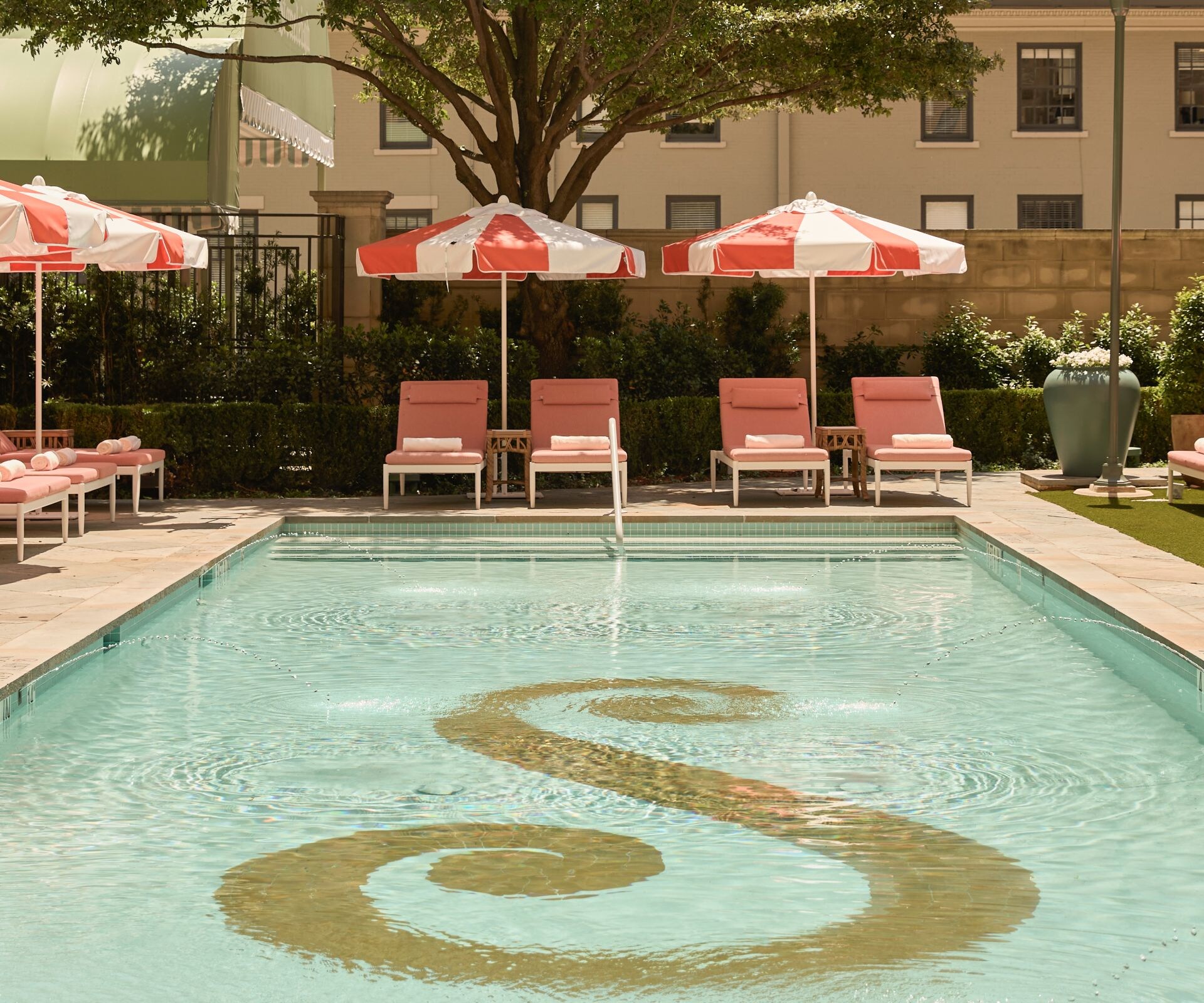Outdoor pool with loungers and red umbrellas