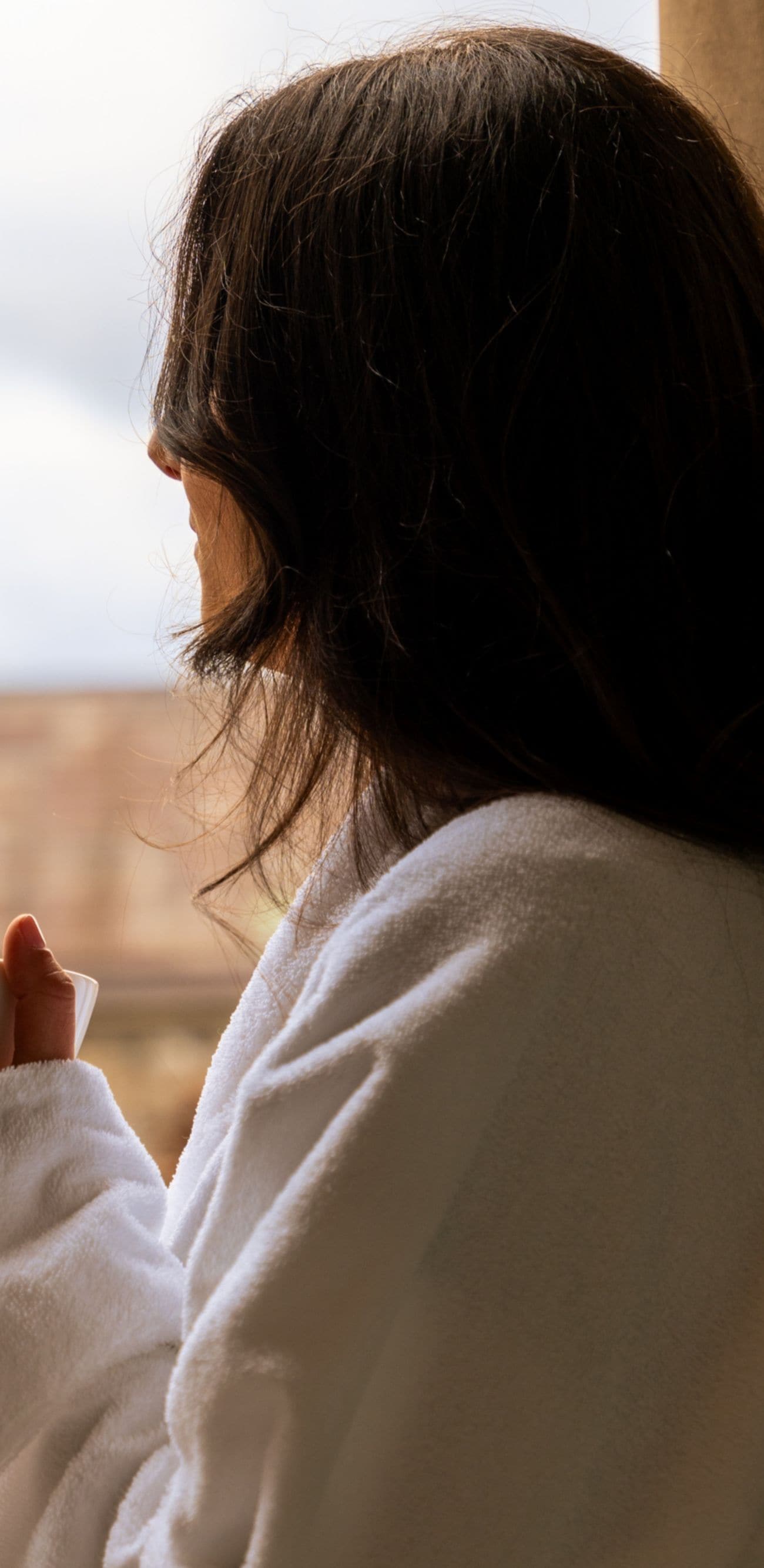 Guest holding a cup of coffee by a balcony door