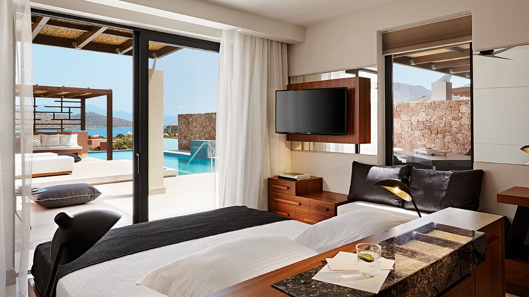 bedroom with double bed, tv and pool with sea view