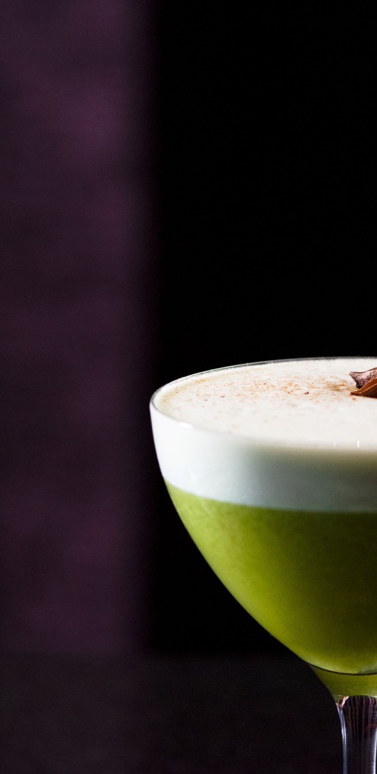 Green cocktail with white foam on top.