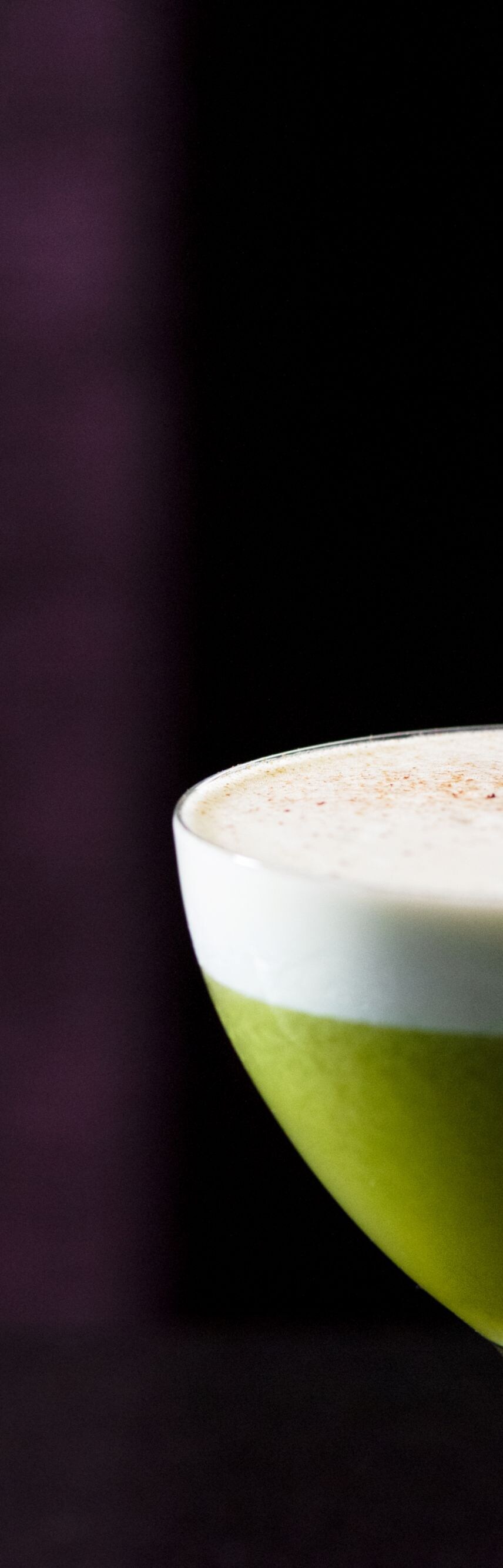 Green cocktail with white foam on top.