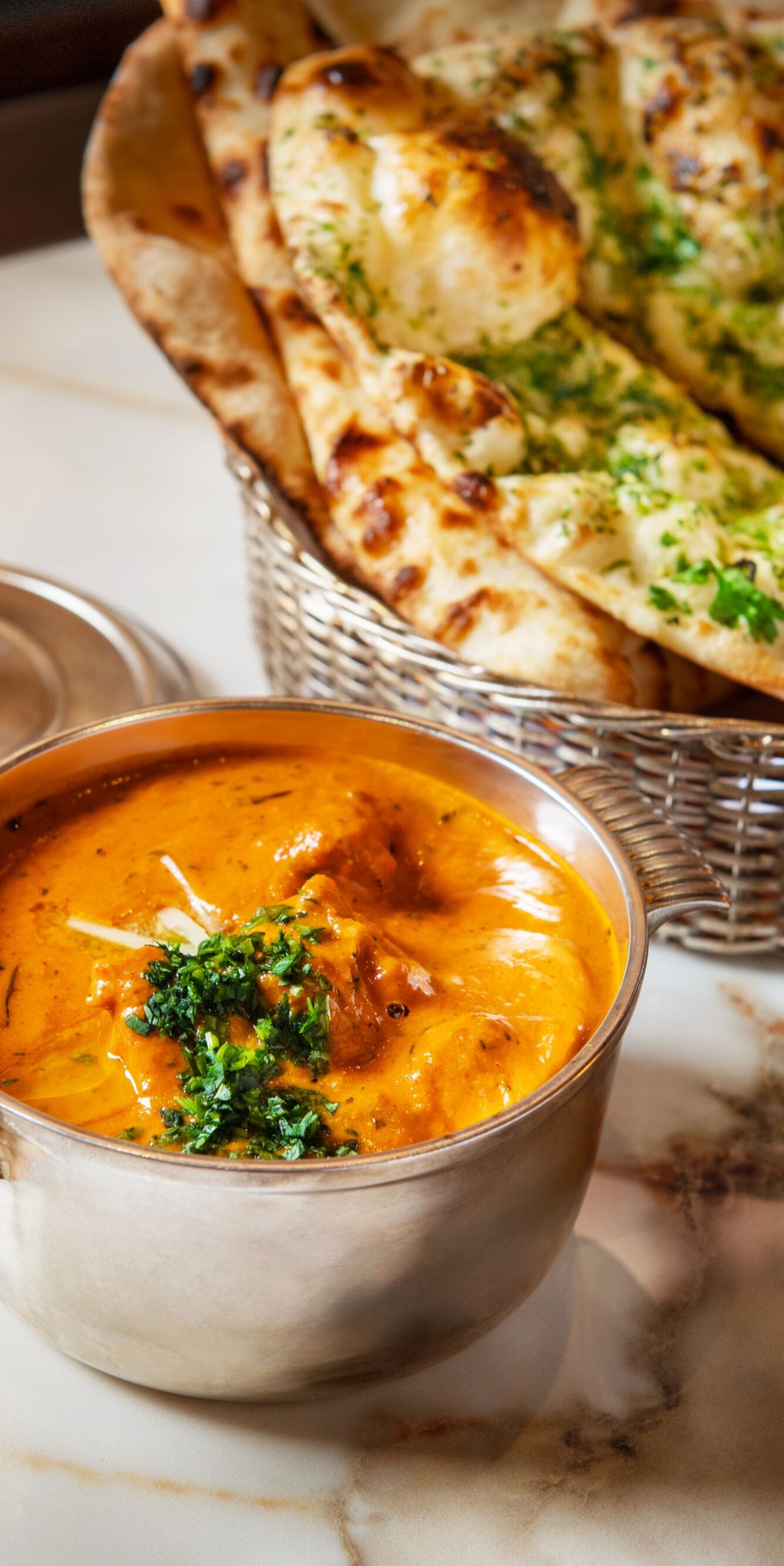Chicken butter masala in bowl, Naan bread basket