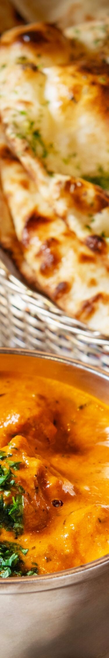Chicken butter masala in bowl, Naan bread basket