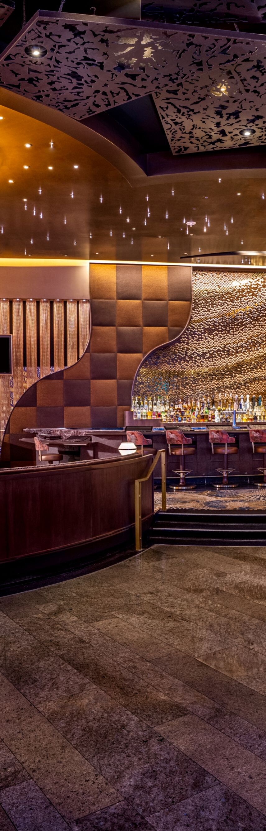 Lighted columns, tables, chairs, TVs on wall.
