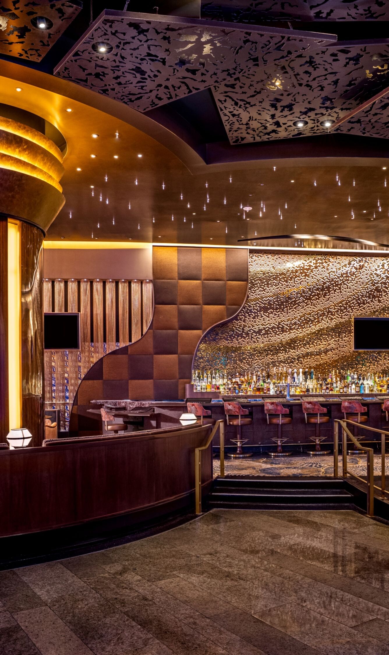 Lighted columns, tables, chairs, TVs on wall.