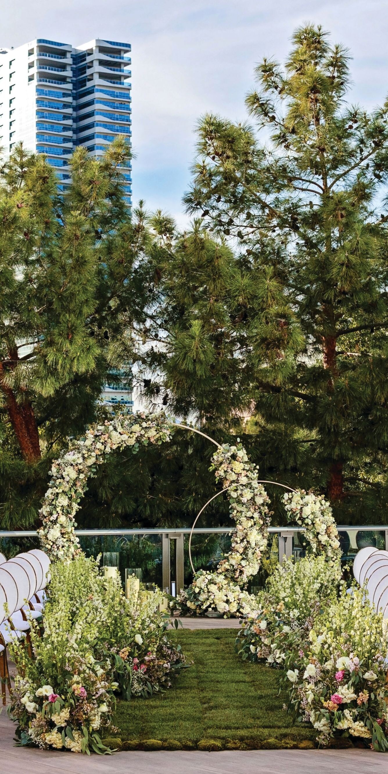 White chairs with grass and flower arch in middle