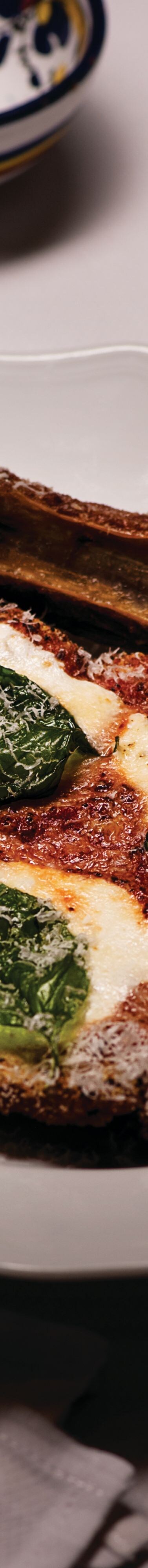 Veal parmesan with bone on white plate.