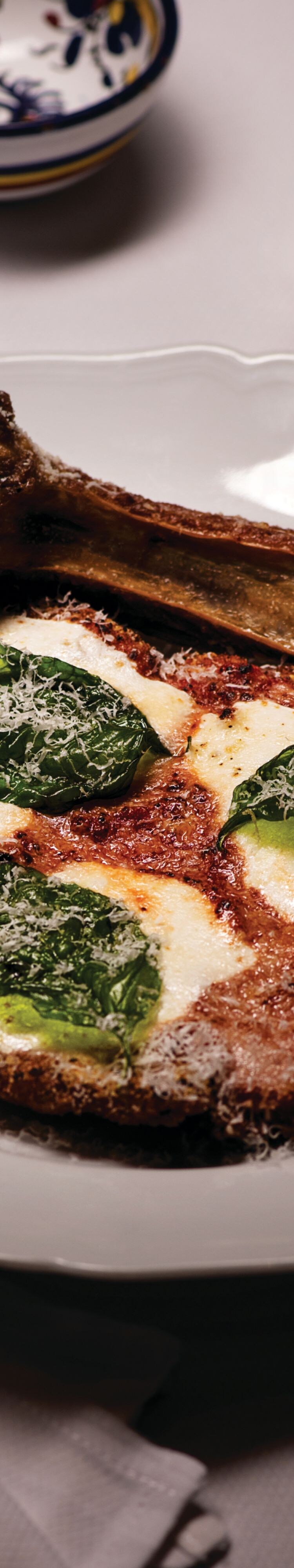 Veal parmesan with bone on white plate.