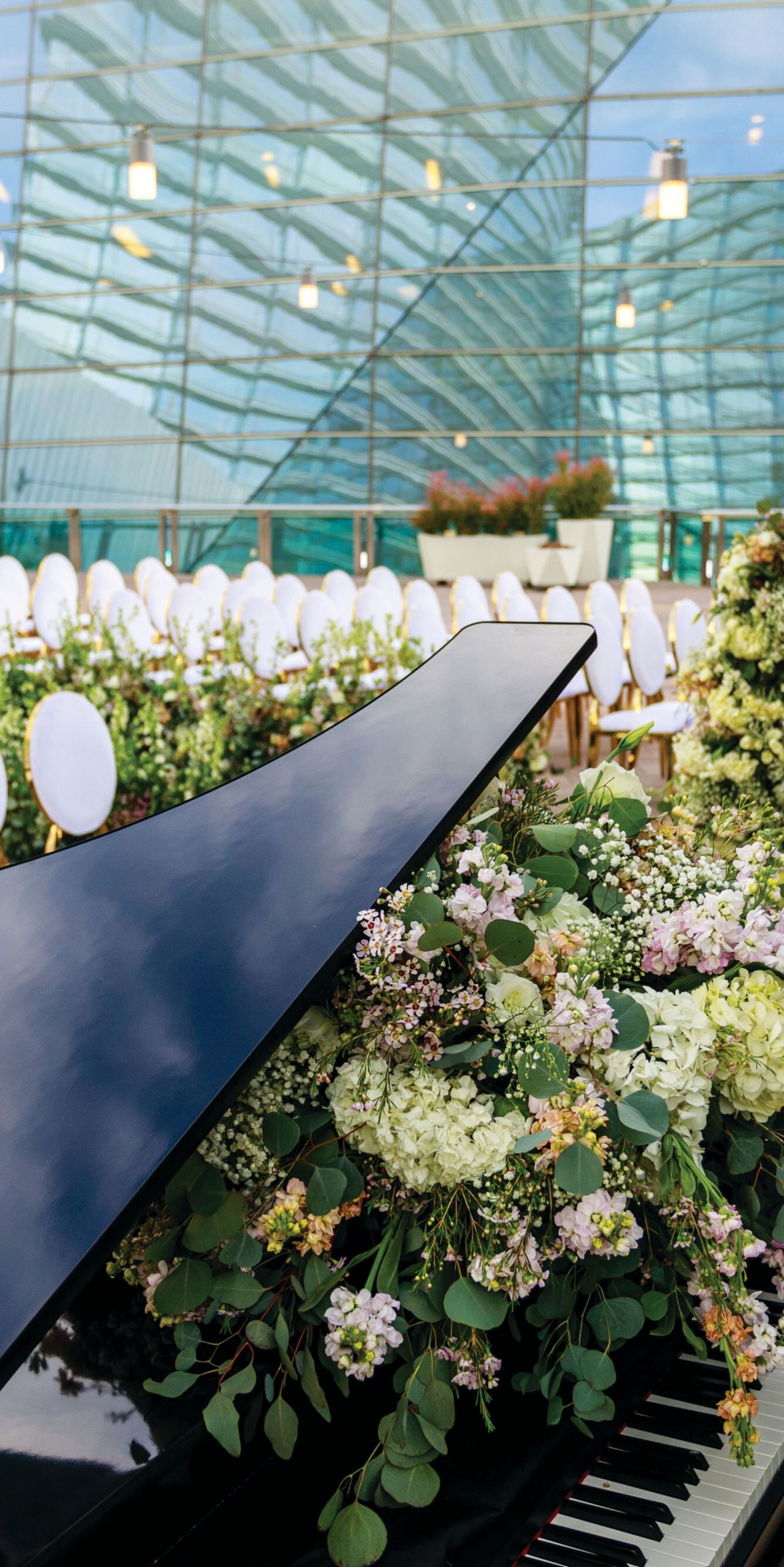 Piano surrounded by flowers and chairs.
