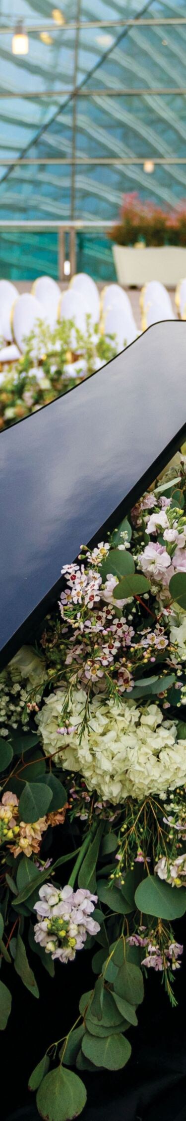 Piano surrounded by flowers and chairs.