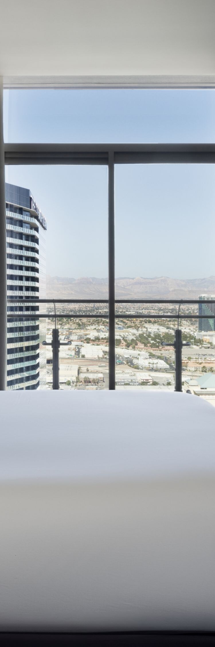 King bed, pillows, TV on wall, glass doors.