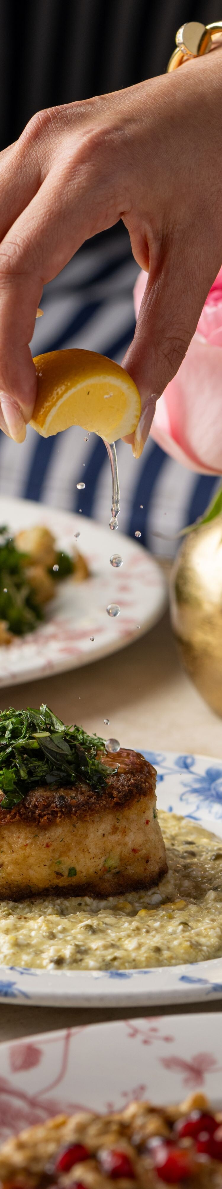 Hand plating crab cake with garnish