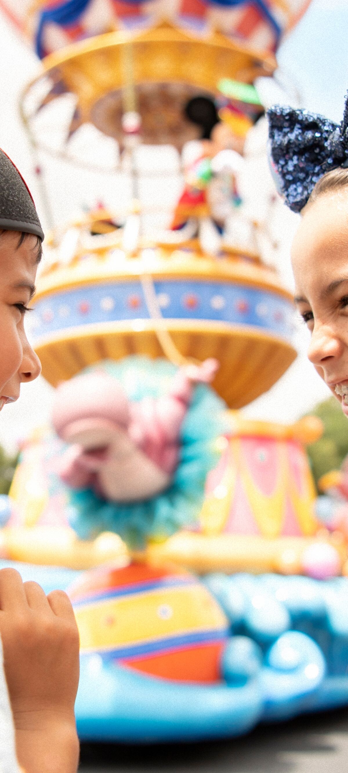 Two kids smiling with mickey mouse ears on.