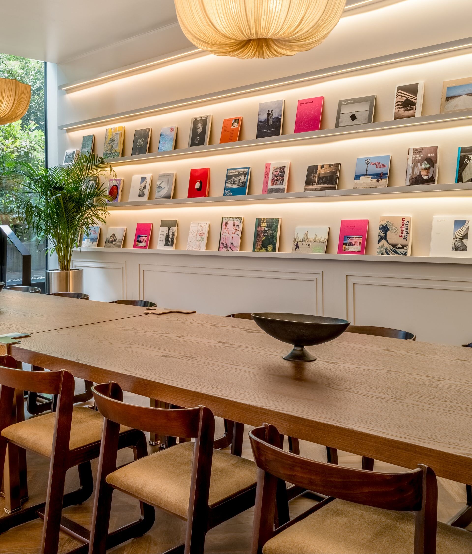 Long wooden table with book display and windows