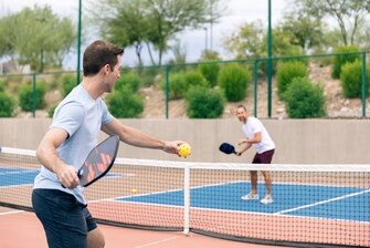 2 men playing pickleball on outdoor court