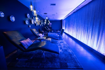 Room with lounge chairs and low blue lighting.