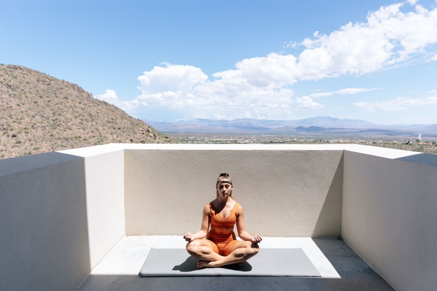 Woman on balcony sitting in yoga position