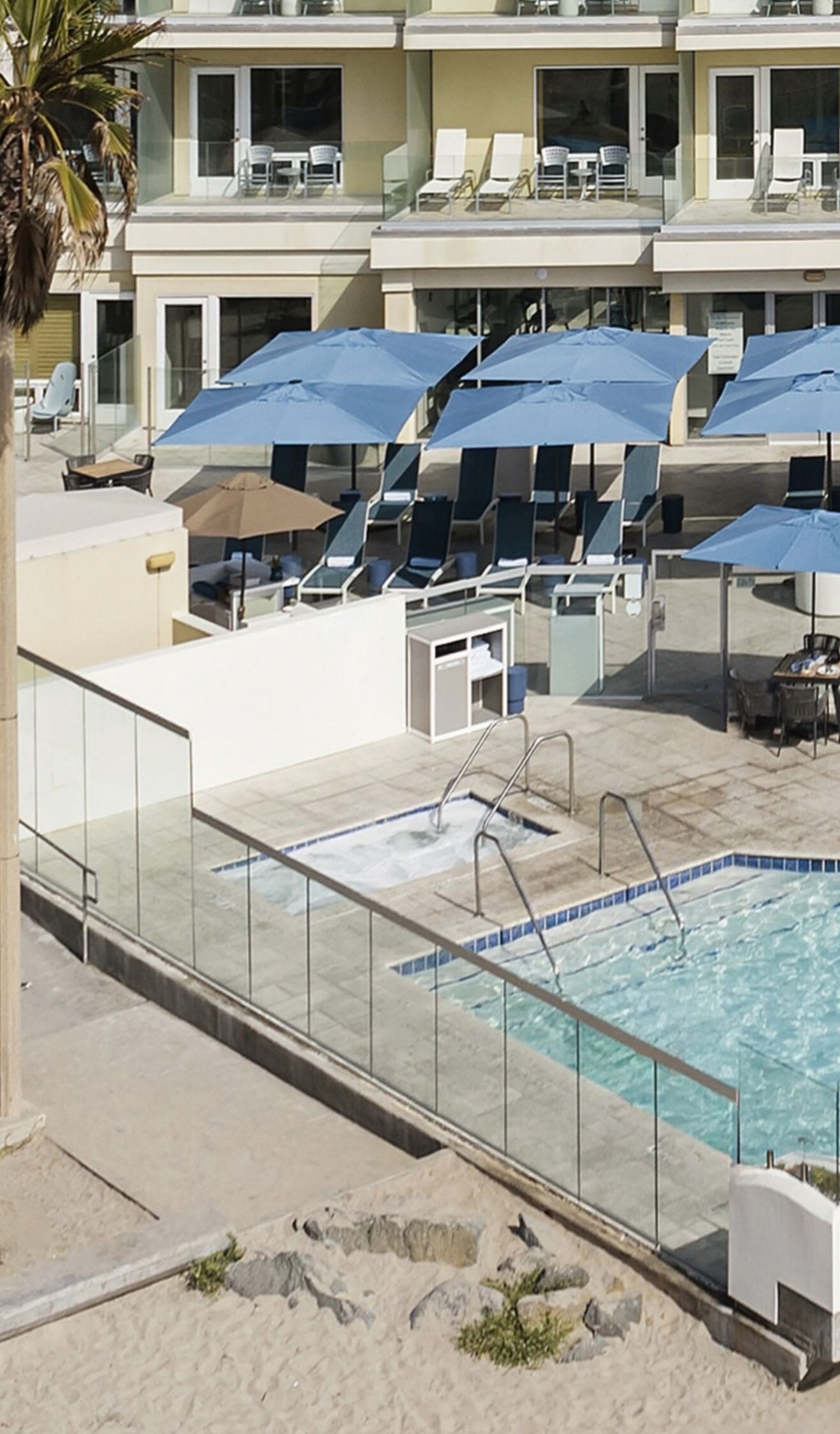 Outdoor whirlpool and pool with palms and loungers