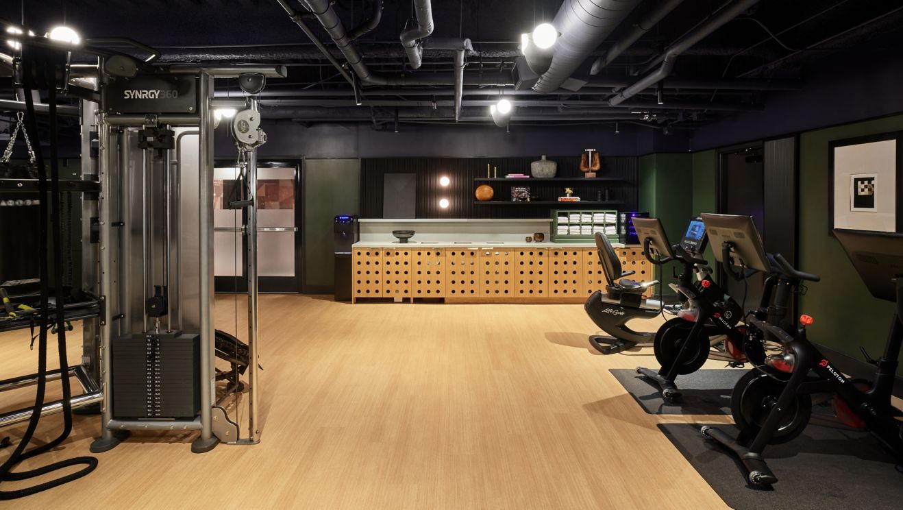 Gym with cardio equipment and amenity bench with t