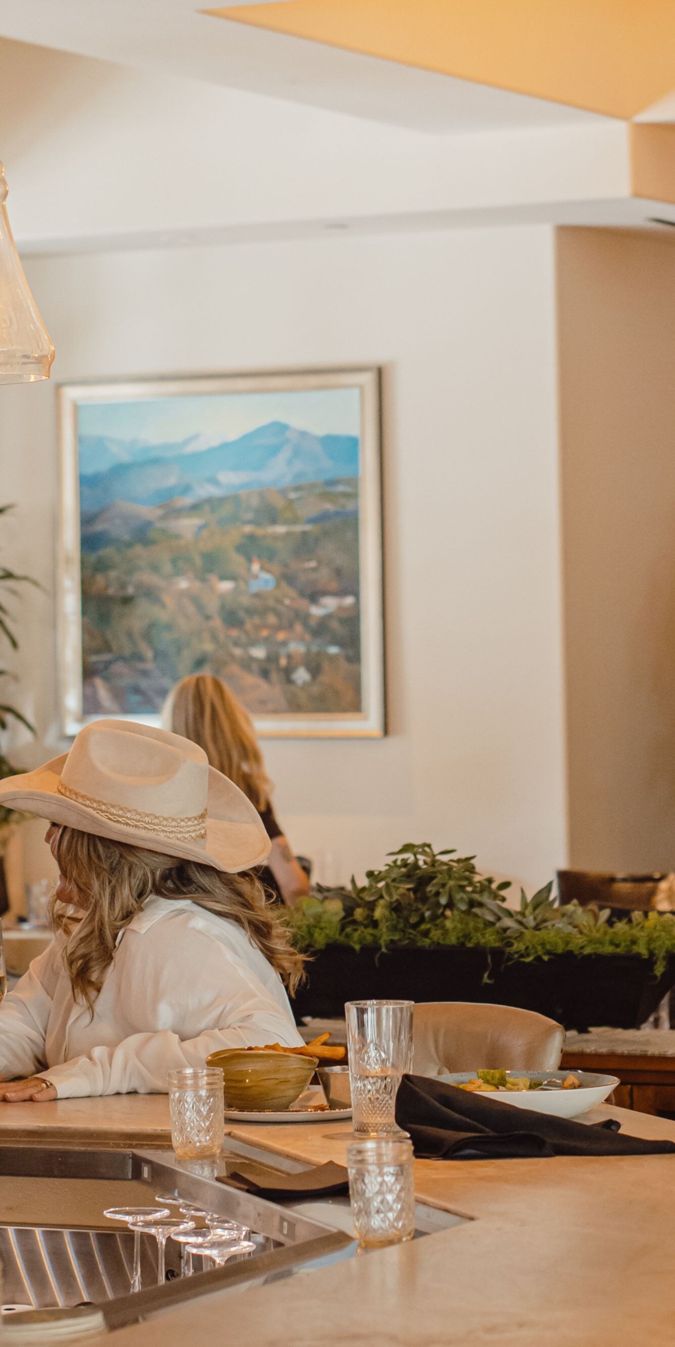 Two guests in cowboy hats sitting at a bar inside 