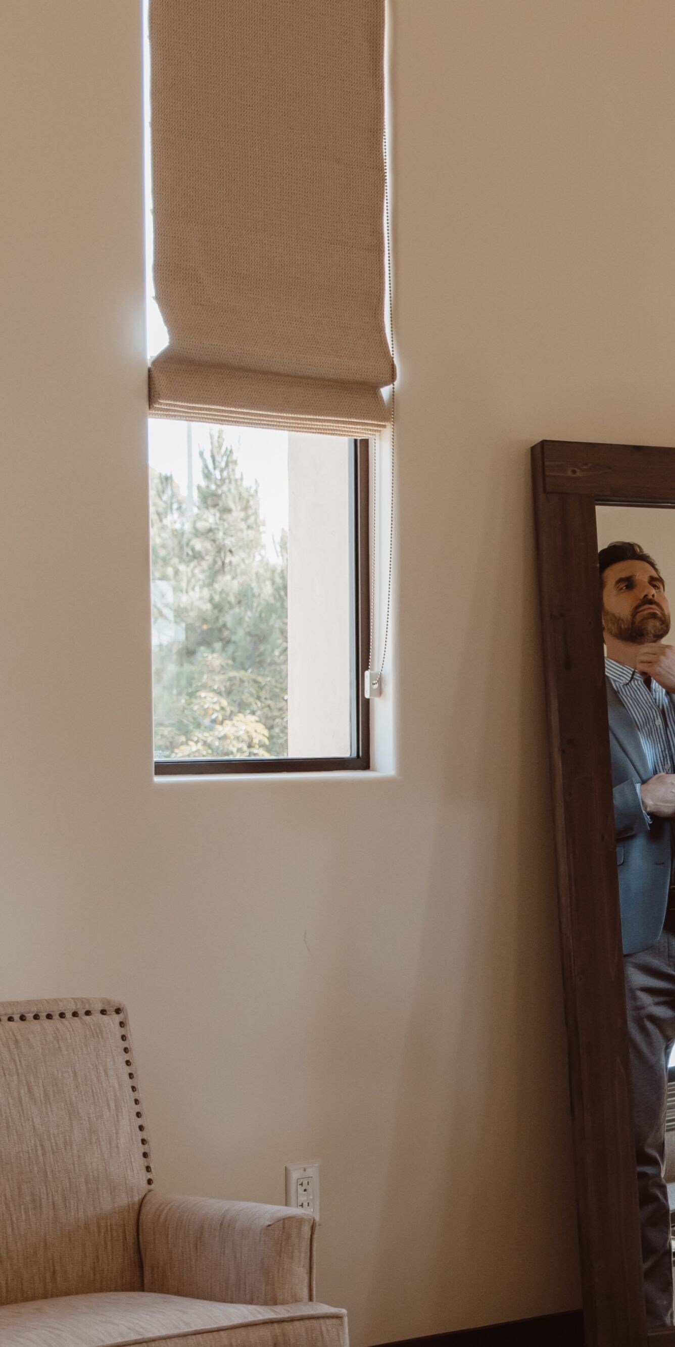 Groom adjusting his suit in front of a mirror in a
