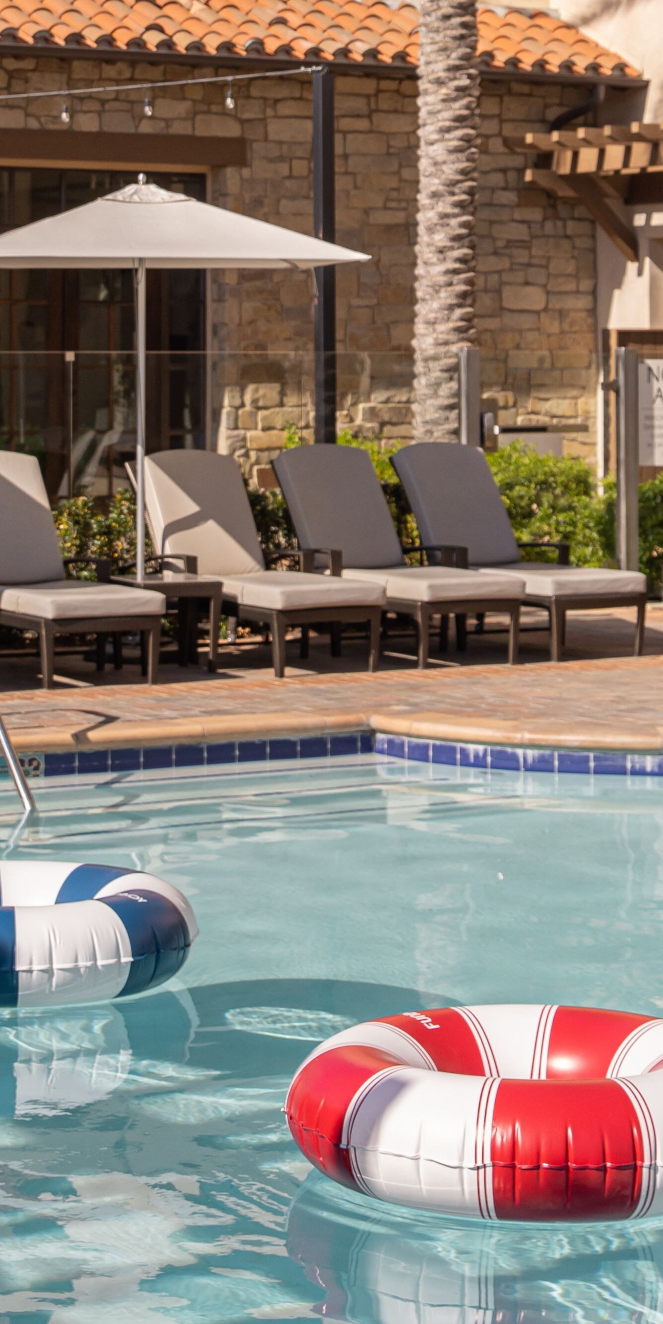 Resort pool with lounge chairs, umbrellas, and flo