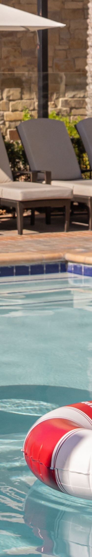 Resort pool with lounge chairs, umbrellas, and flo