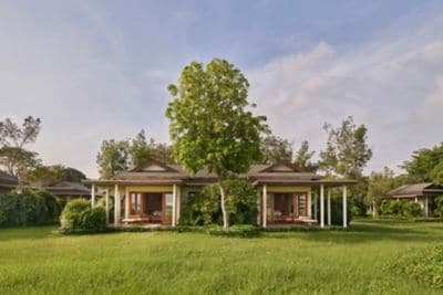 A bungalow set amid greenery and water views.