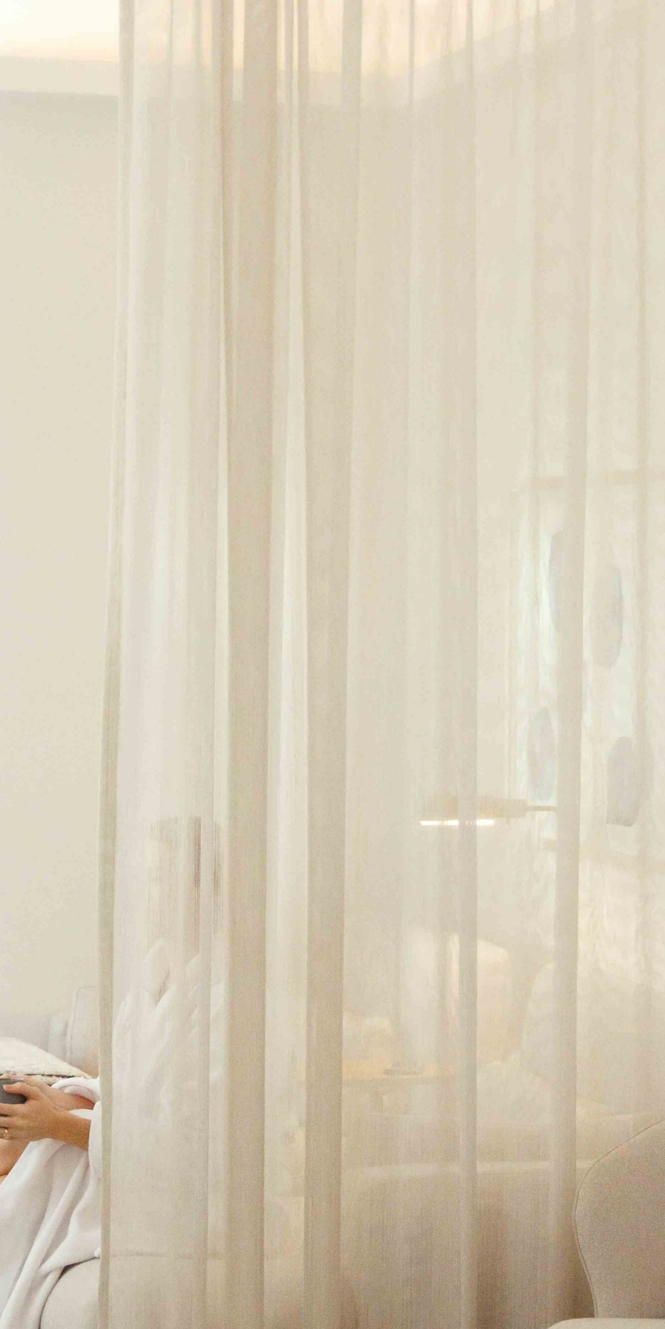 Des rideaux transparents filtrent la lumière du jour dans un hôtel.