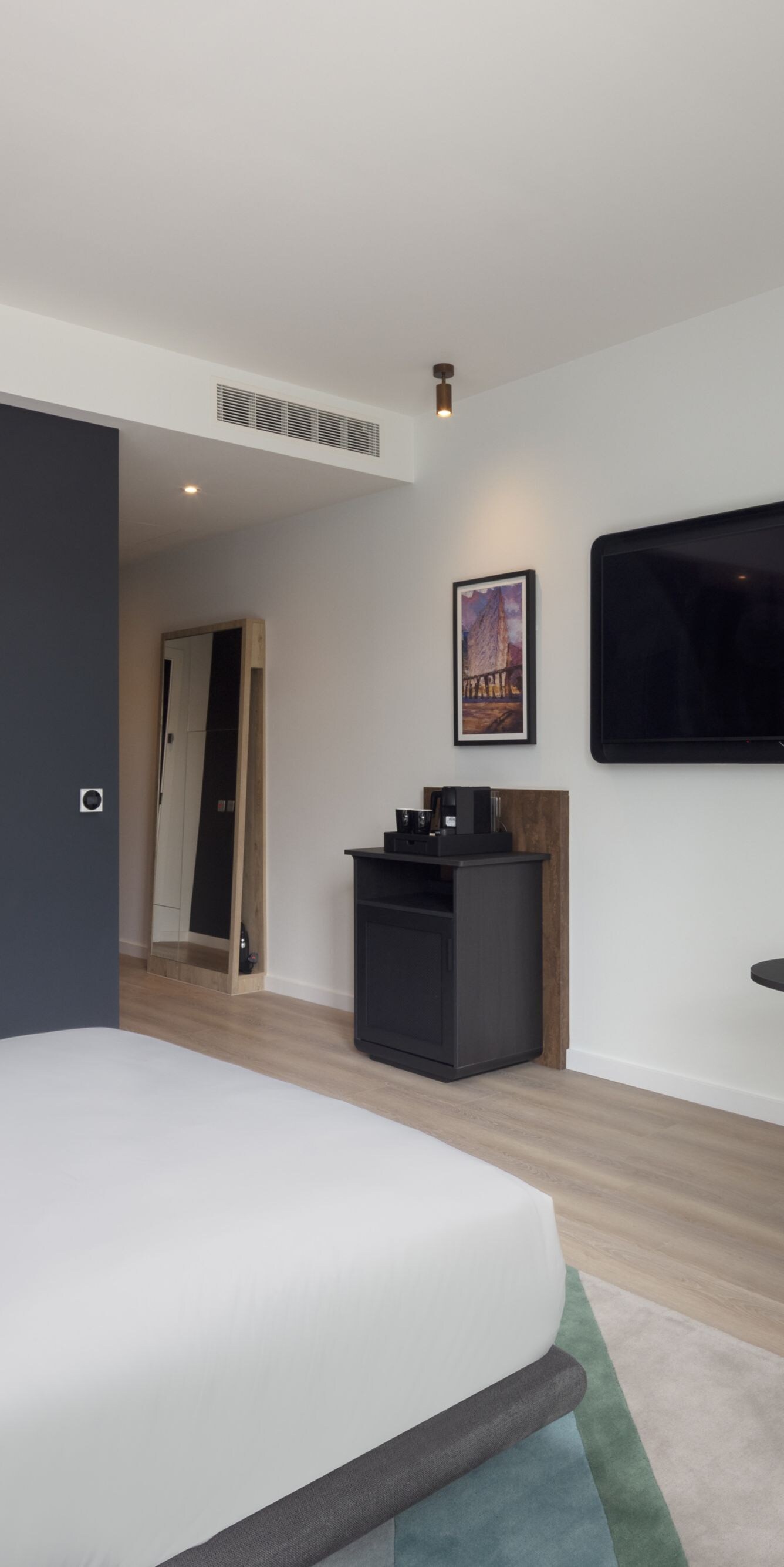 Hotel room with bed, sofa, and wall TV