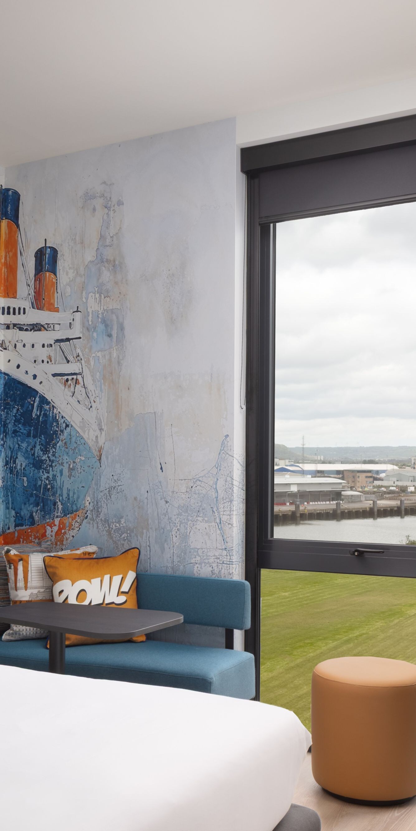 Hotel room with ship mural and river view window