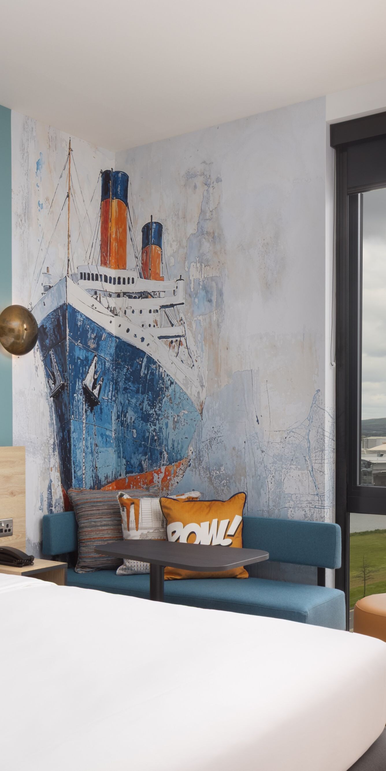 Hotel room with ship mural and window view