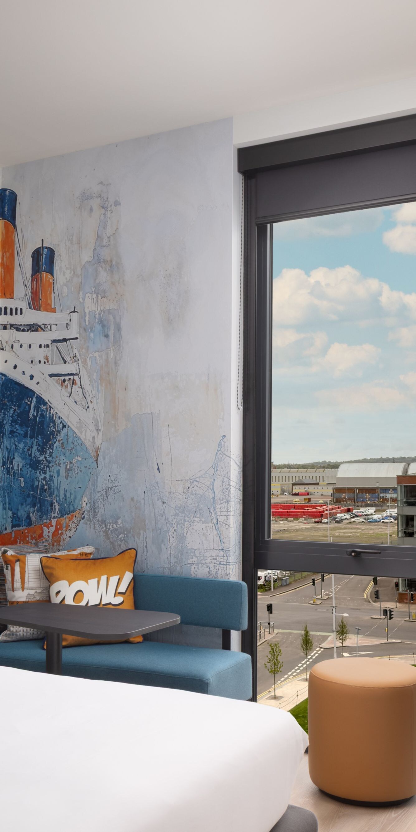 Hotel room with bed ship mural and city view