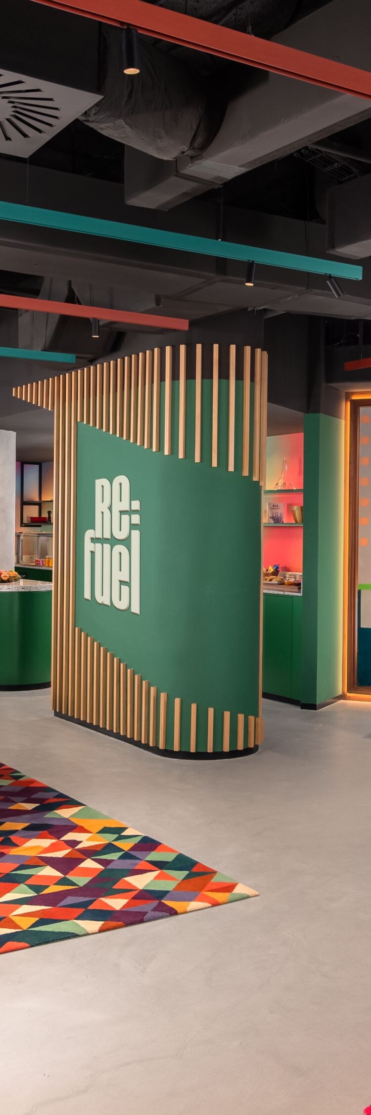 Área del lobby con sofá verde, alfombra y mostrador de recepción