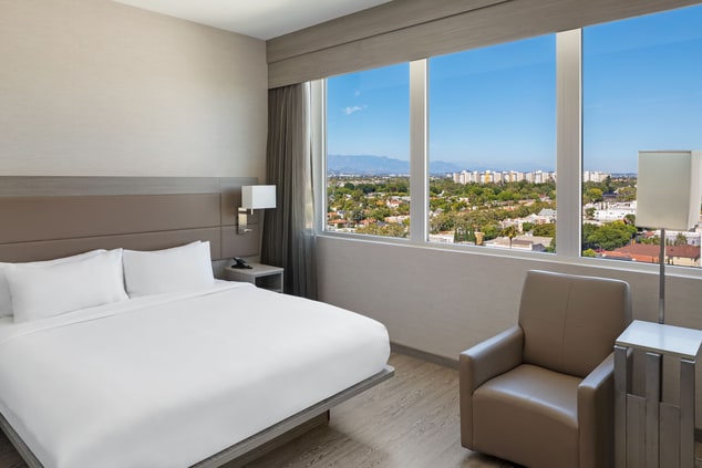 Guest room with a bed, chair, and a city view