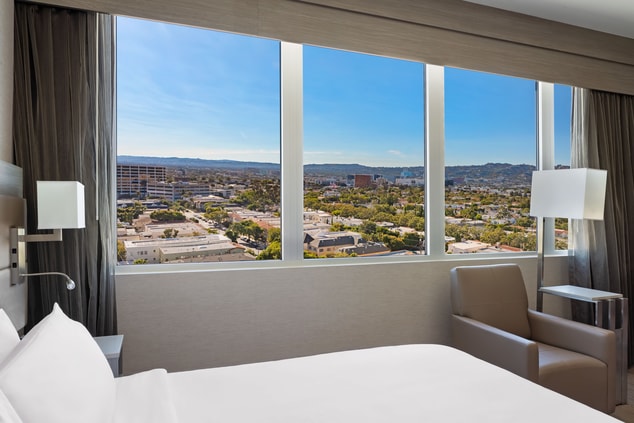 Guestroom with a bed and large city view window