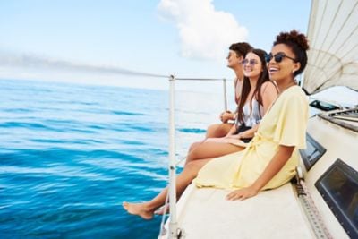 Women sitting on the side of a sailboat at sea