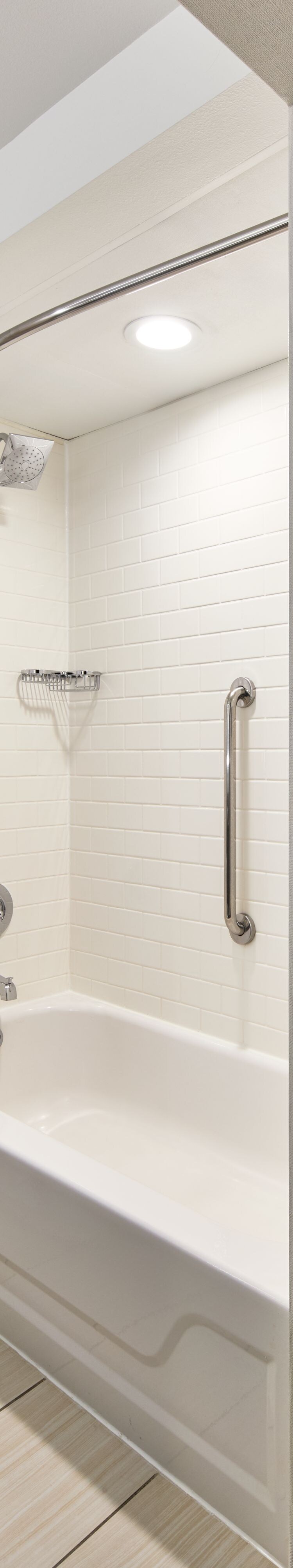 Bathroom with a shower/tub combo and light decor.