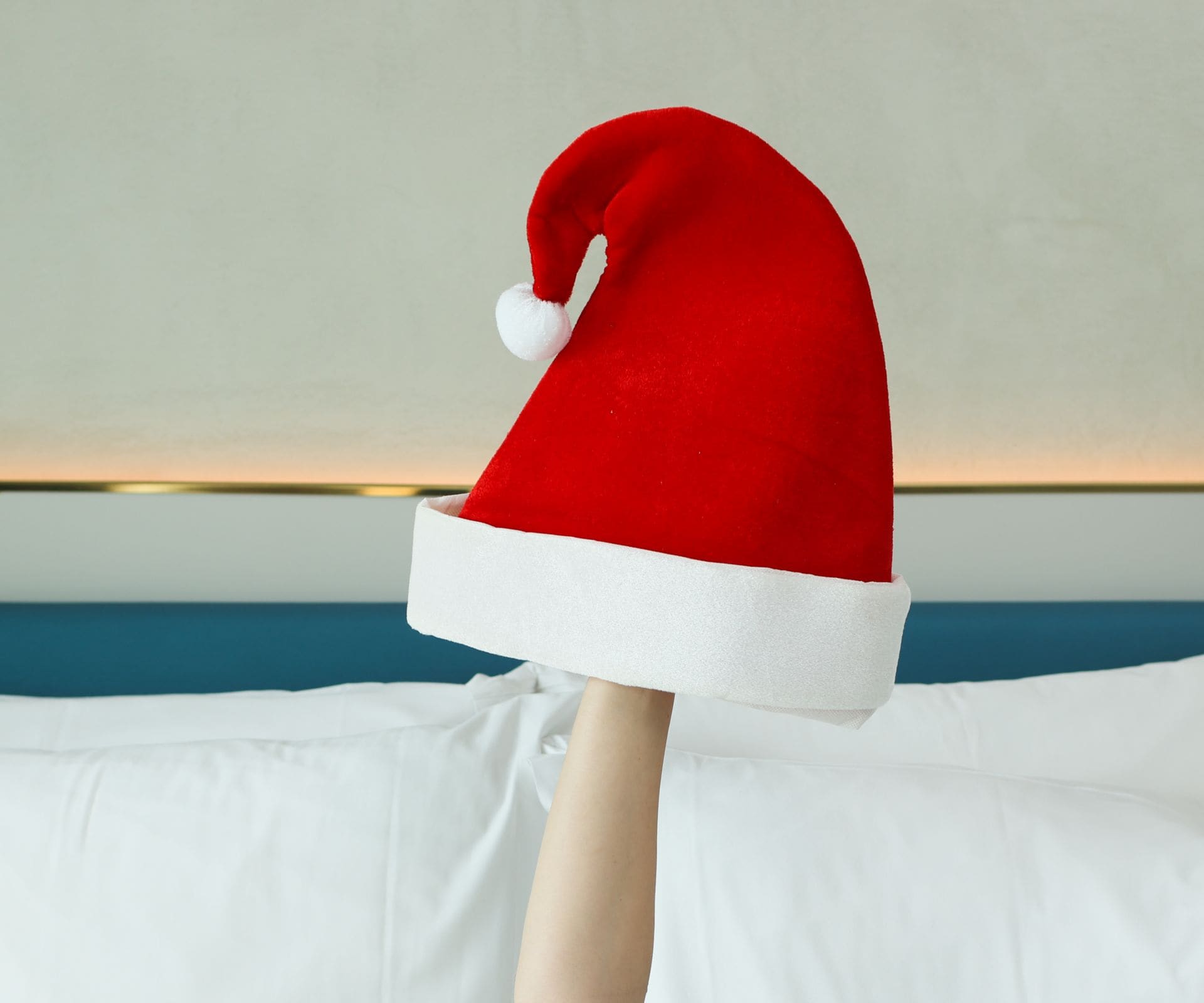An arm in a bed with a Santa Claus hat 