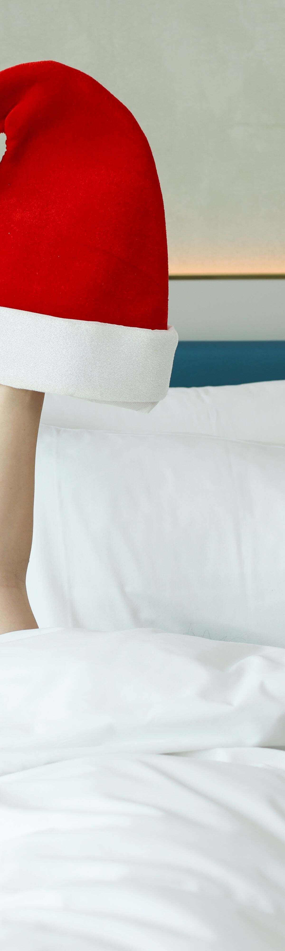 An arm in a bed with a Santa Claus hat 