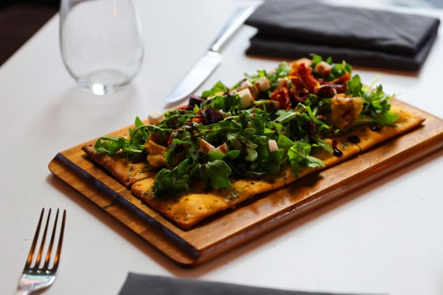 flatbread topped with leafy greens on a table