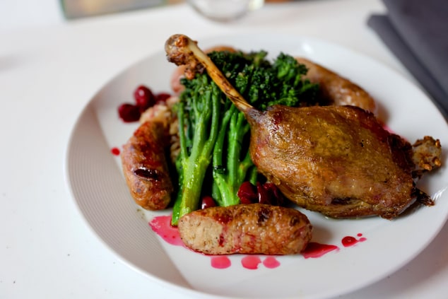 Duck leg confit with broccolini on a plate