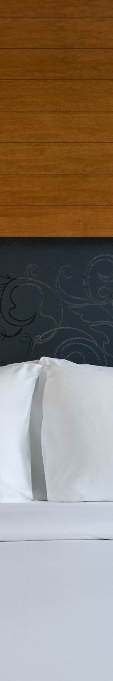 モダンなホテルのキングベッド、木製ヘッドボード、照明