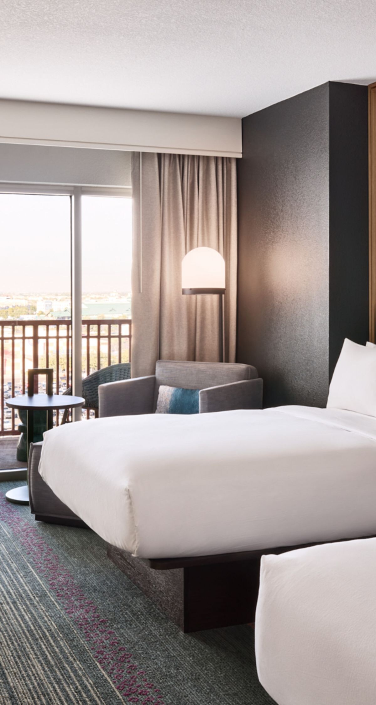 Modern hotel room with two queen beds, desk, armch