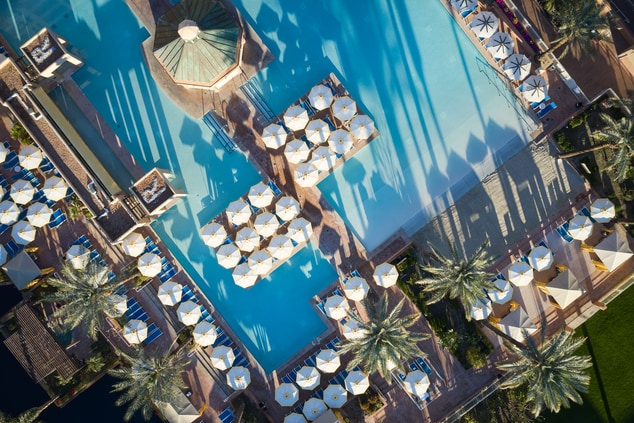 Aerial of pool with open umbrellas and blue water