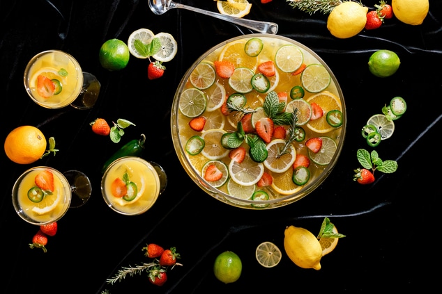 Punch bowl filled with fruit with glasses around 