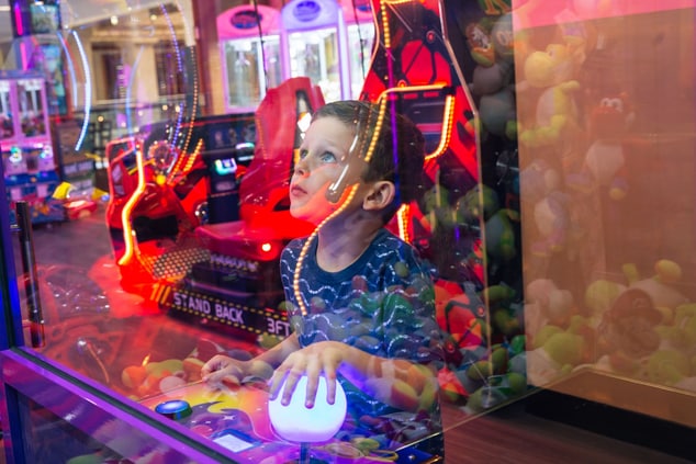 Kid playing a game in an arcade. 