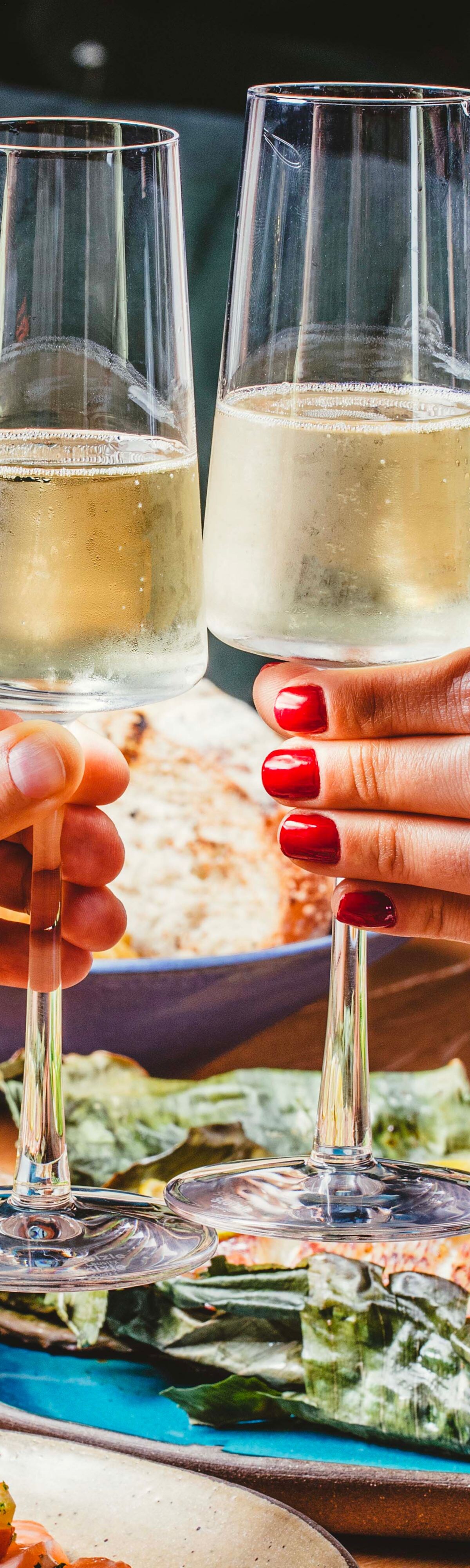 duas mãos brindando com taças de vinho